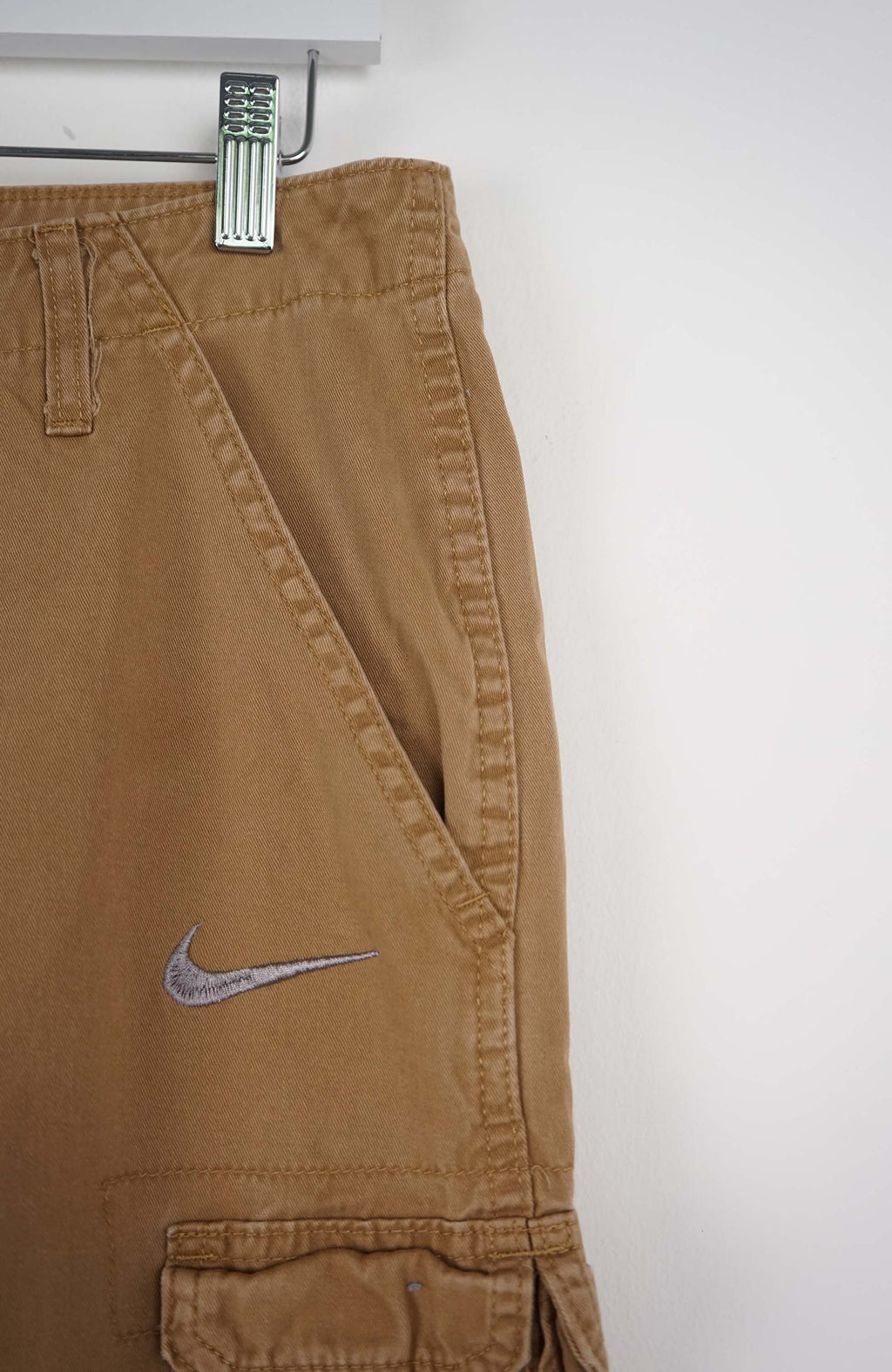 Tan cargo shorts with a Nike logo on a white background