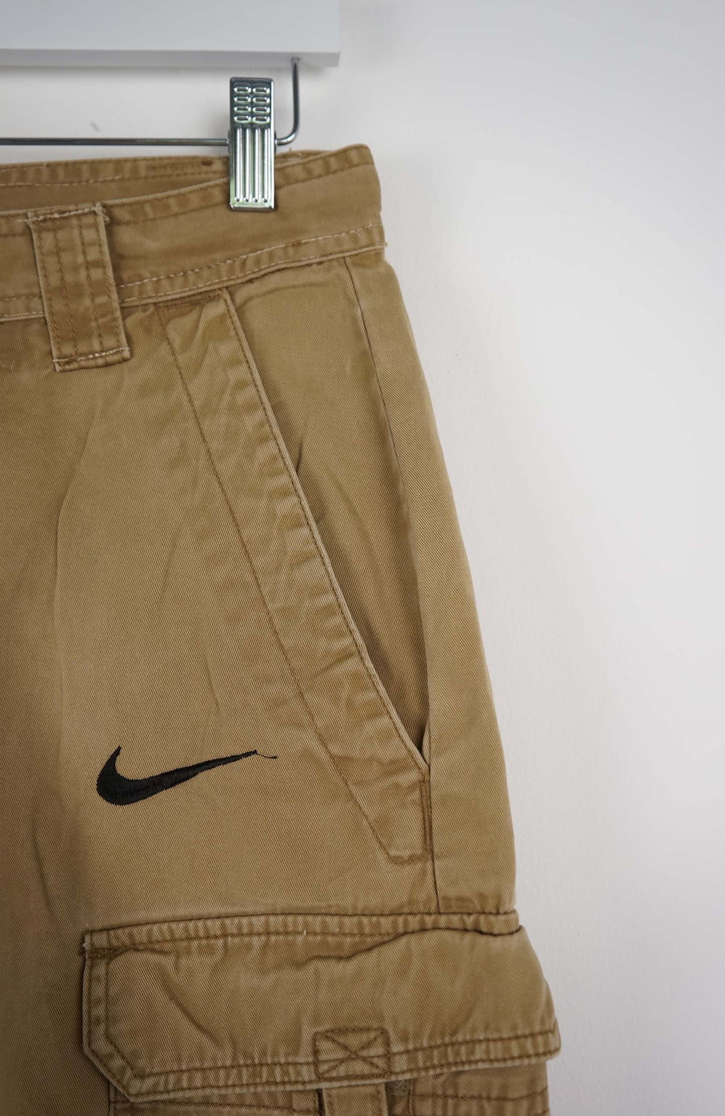 Beige cargo shorts with a Nike logo on a white background