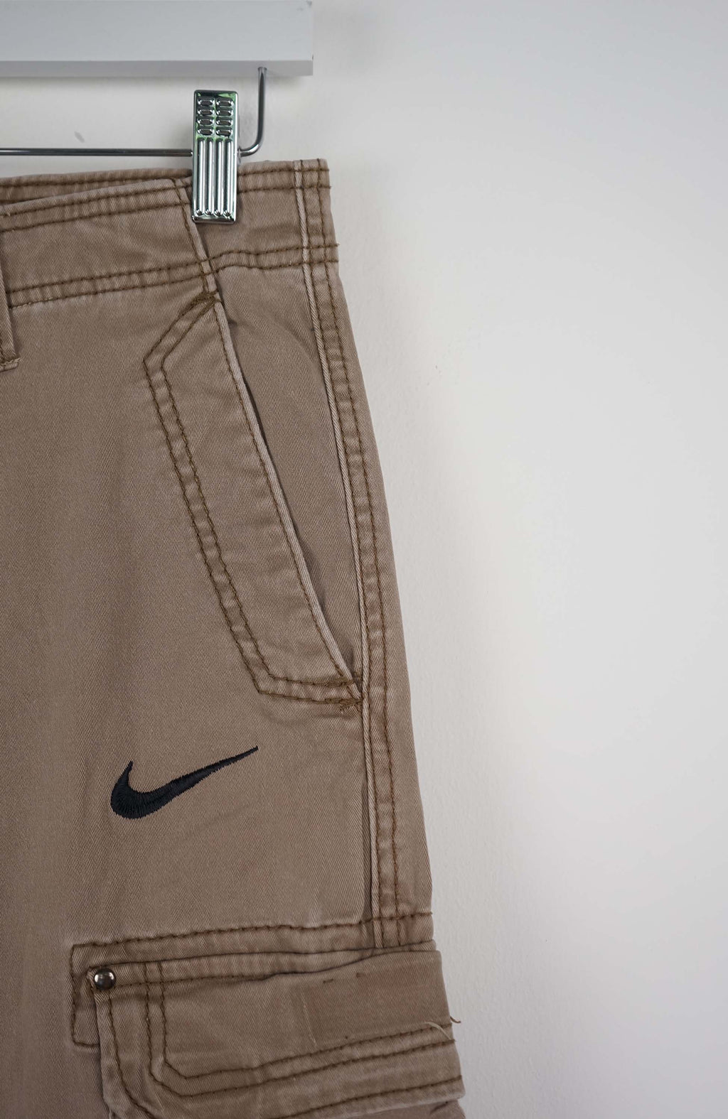 Beige cargo shorts with a Nike logo on a white background