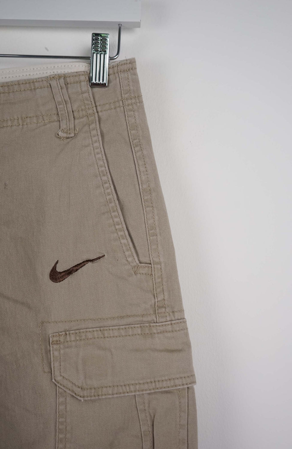 Beige cargo shorts with a Nike logo on a white background