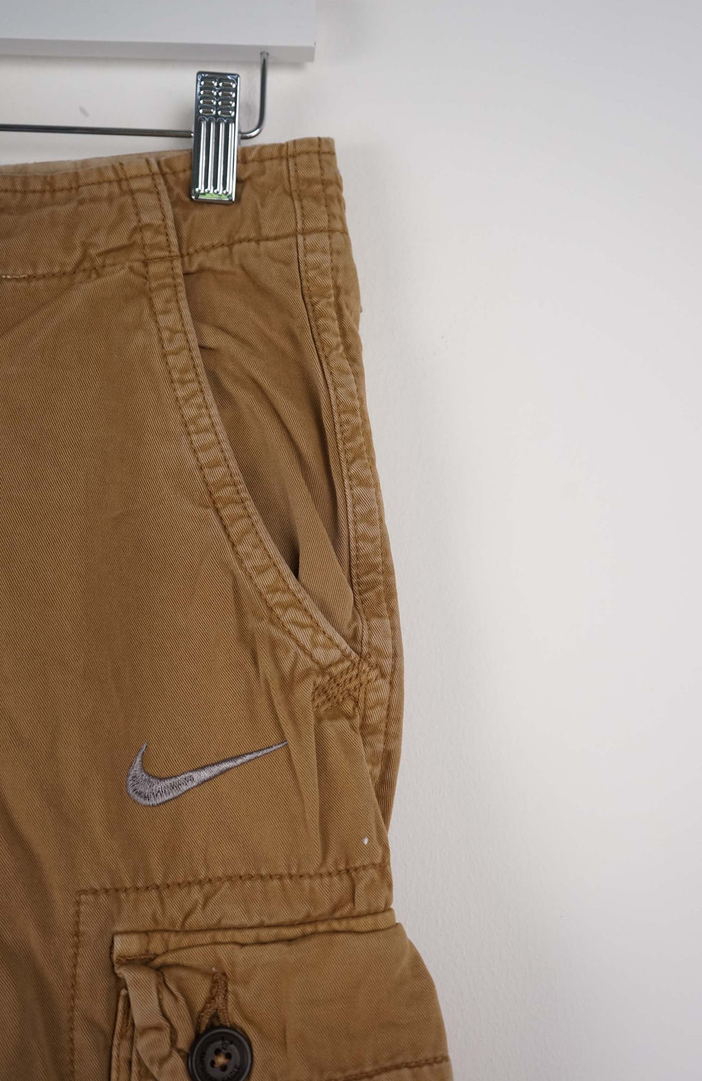 Beige cargo shorts with a Nike logo on a white background