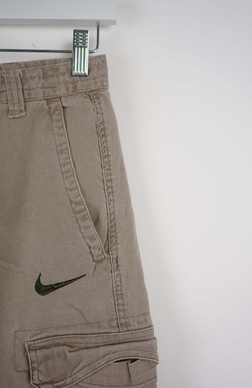 Beige cargo shorts with a Nike logo on a white background