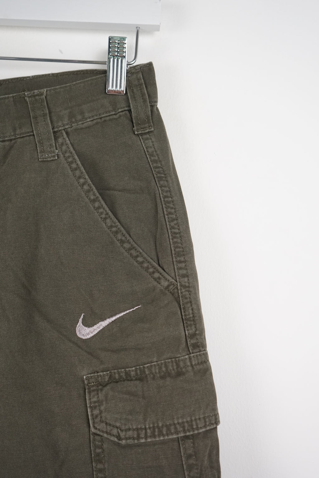 Green cargo shorts with a Nike logo on a white background