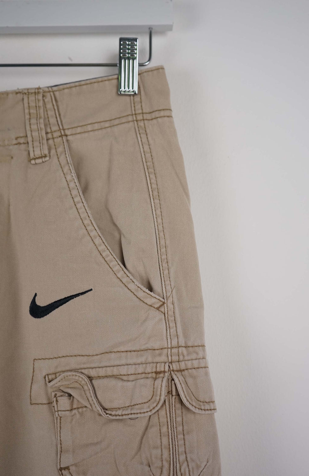 Beige cargo shorts with a Nike logo on a white background