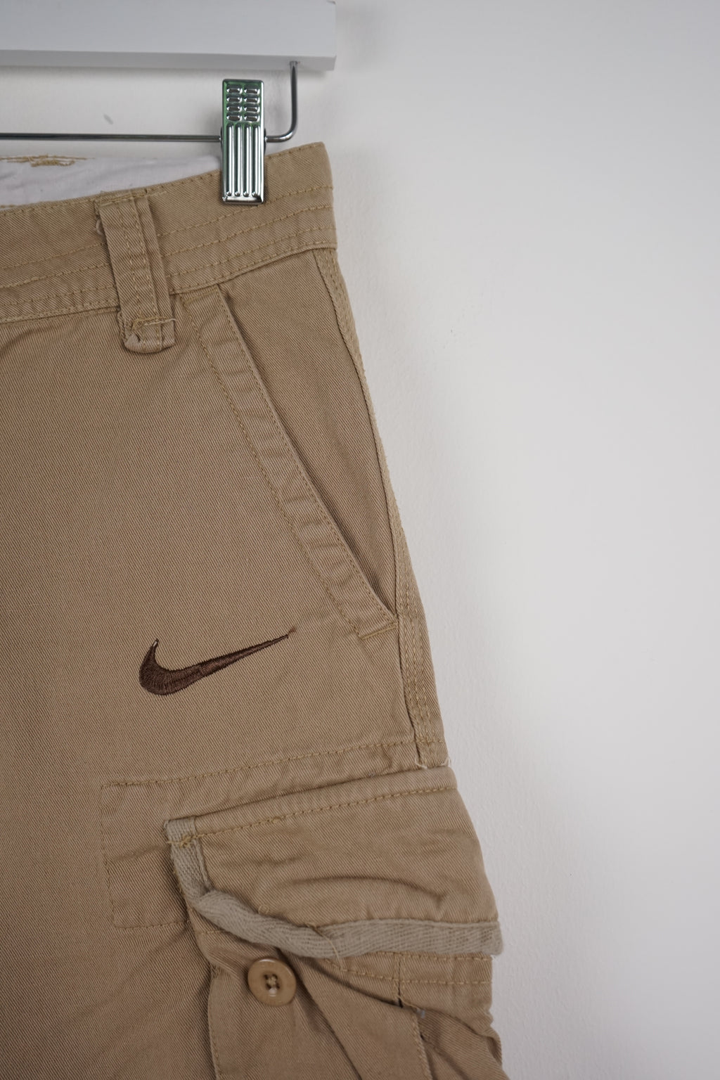 Beige cargo shorts with a Nike logo on a white background