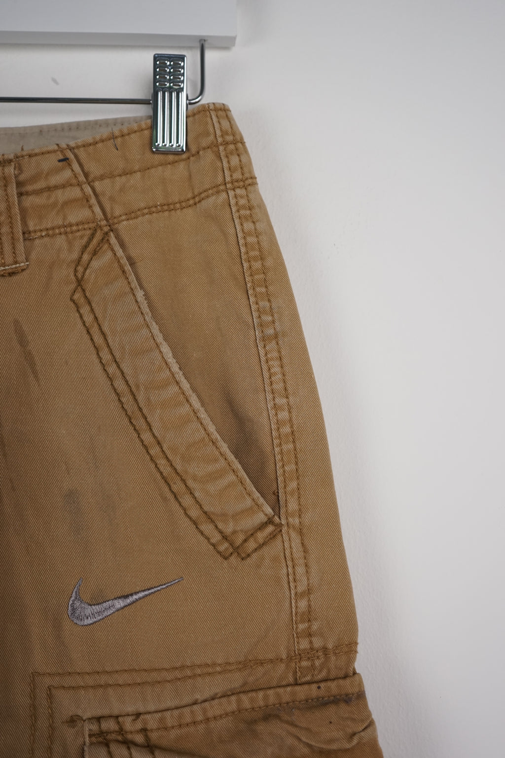 Beige cargo shorts on a white hanger with a white background