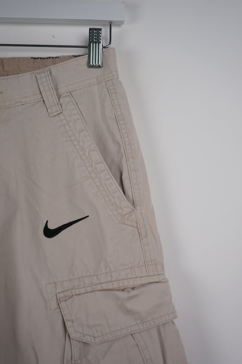 Beige cargo shorts with a Nike logo on a white background