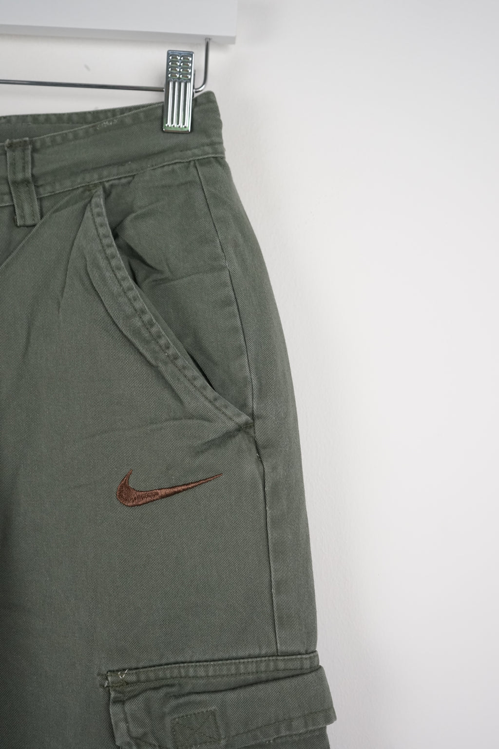 Green cargo shorts with a Nike logo on a white background