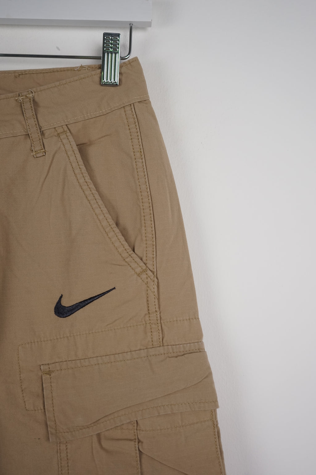 Beige cargo shorts with a Nike logo on a white background