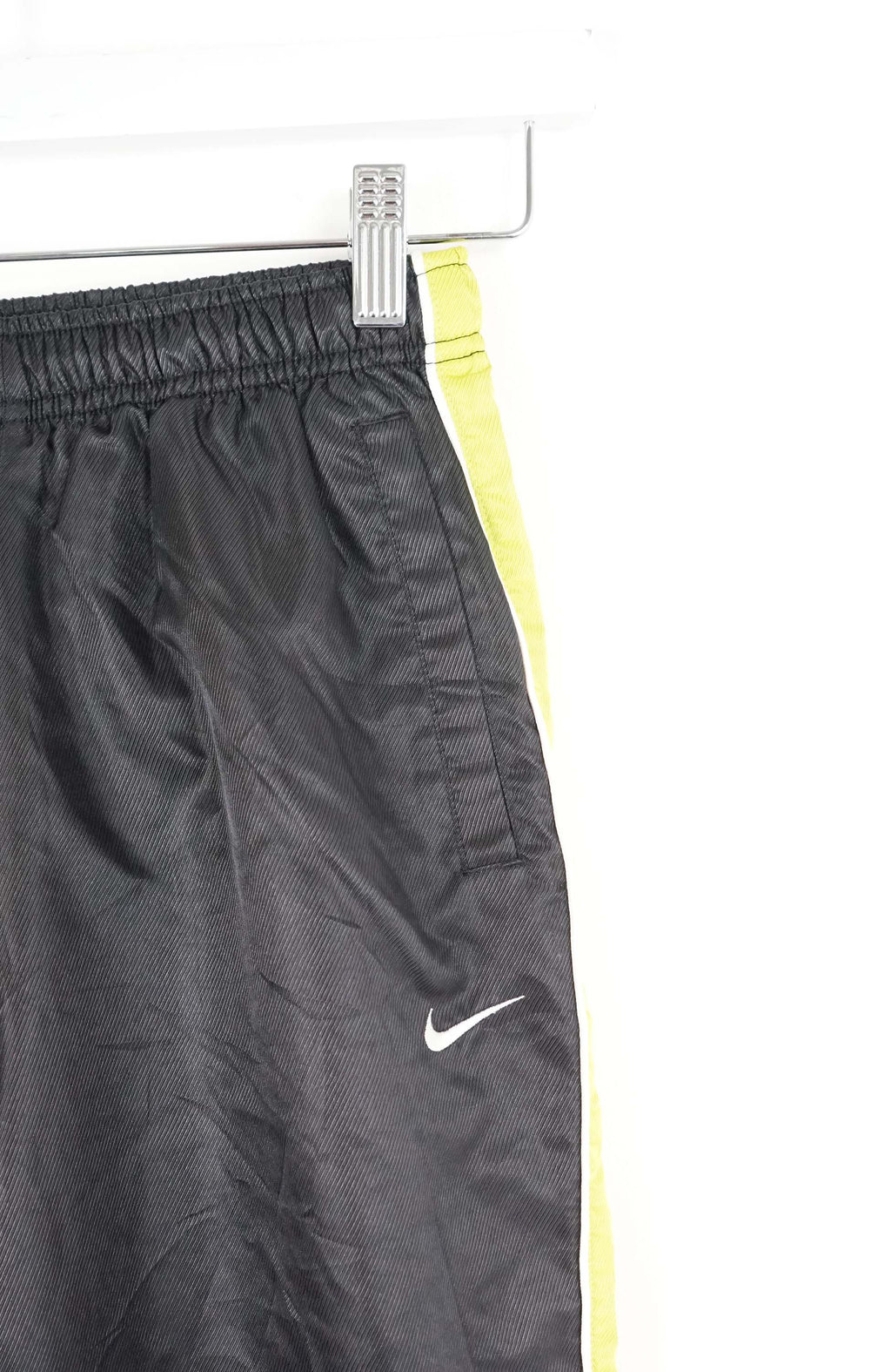 Black athletic pants with yellow stripes on a white background