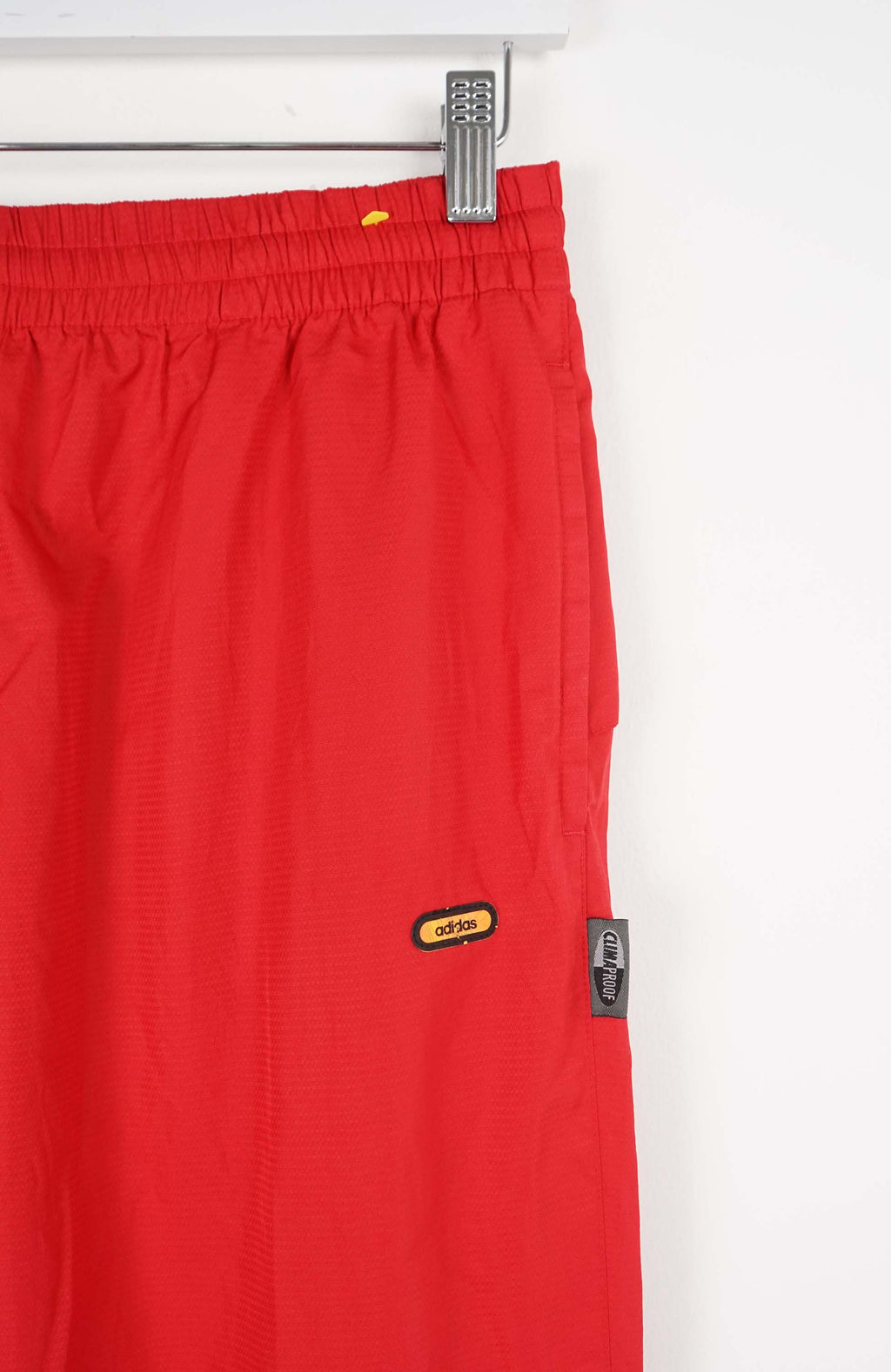 Red pants hanging on a white rack against a white background