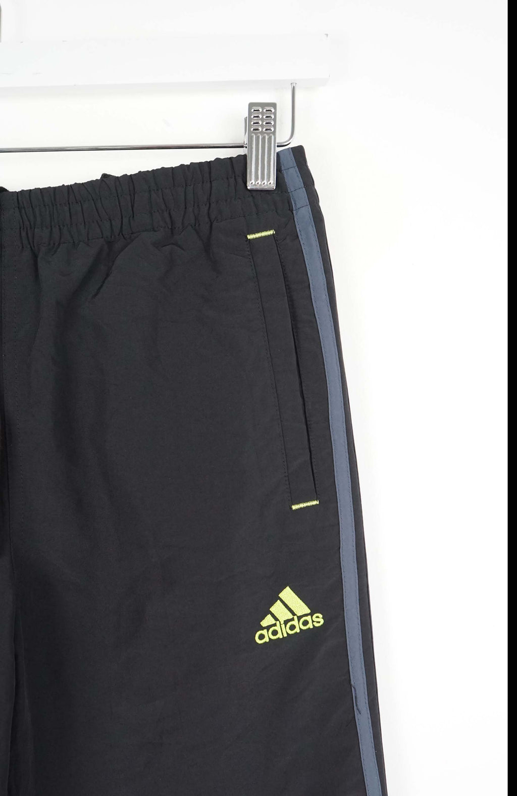 Black Adidas pants with a yellow logo on a white background