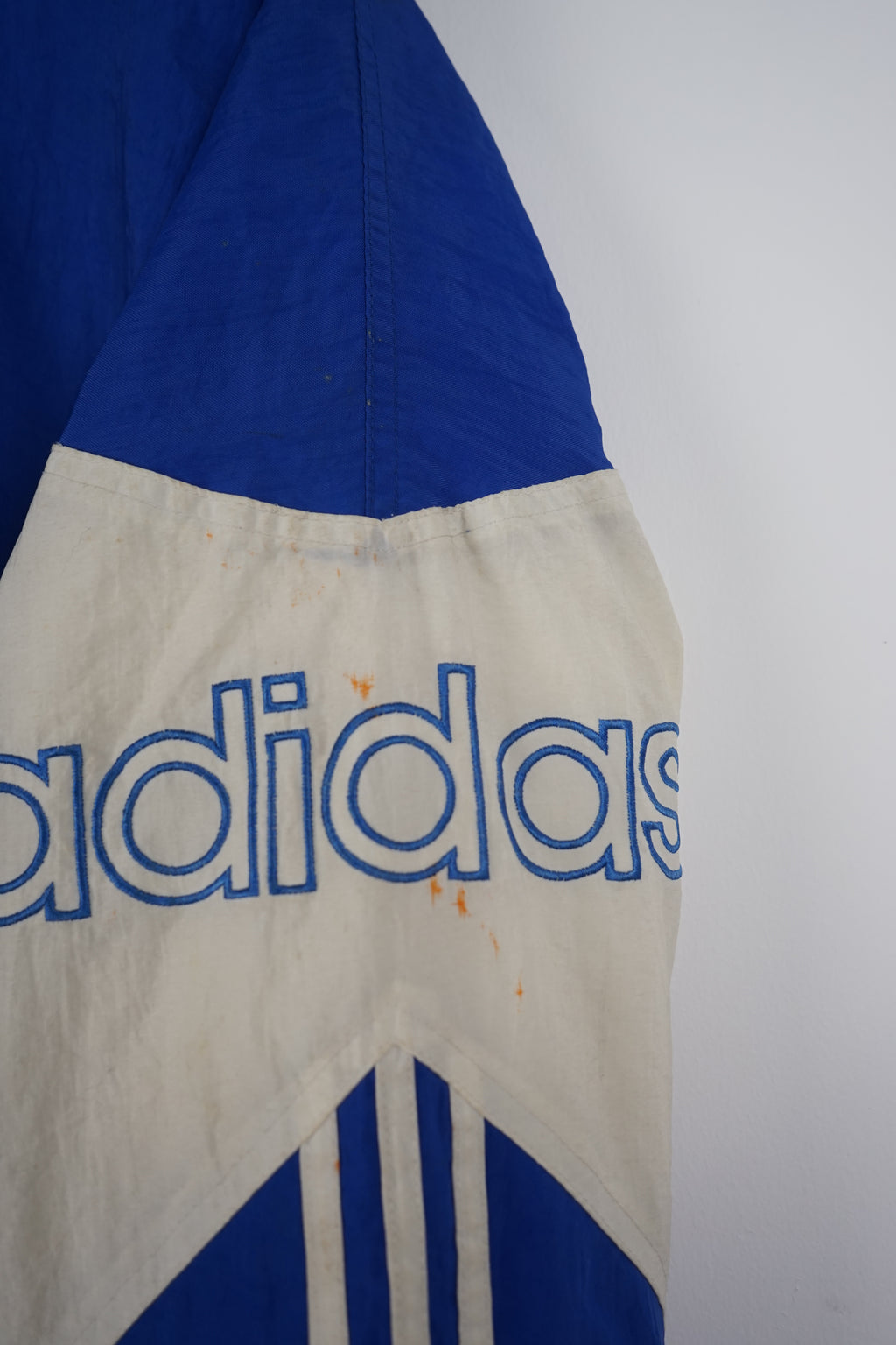 Blue and white Adidas jacket with brand logos on a white background