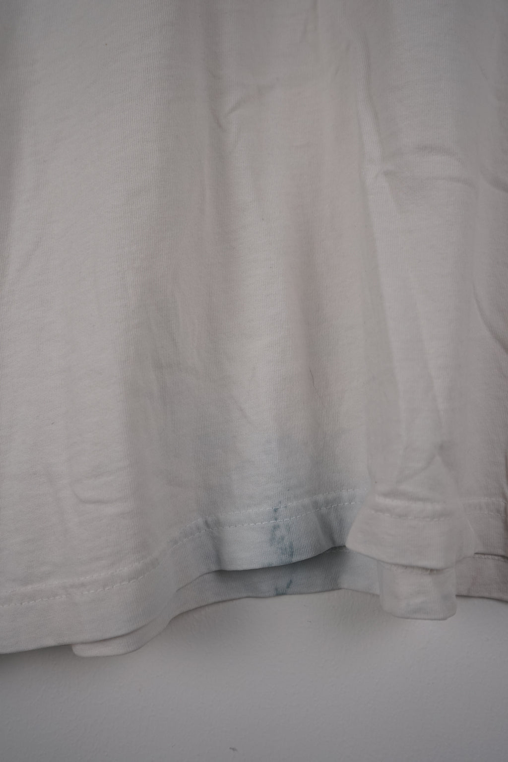 White t-shirt with a black logo on a hanger against a white background
