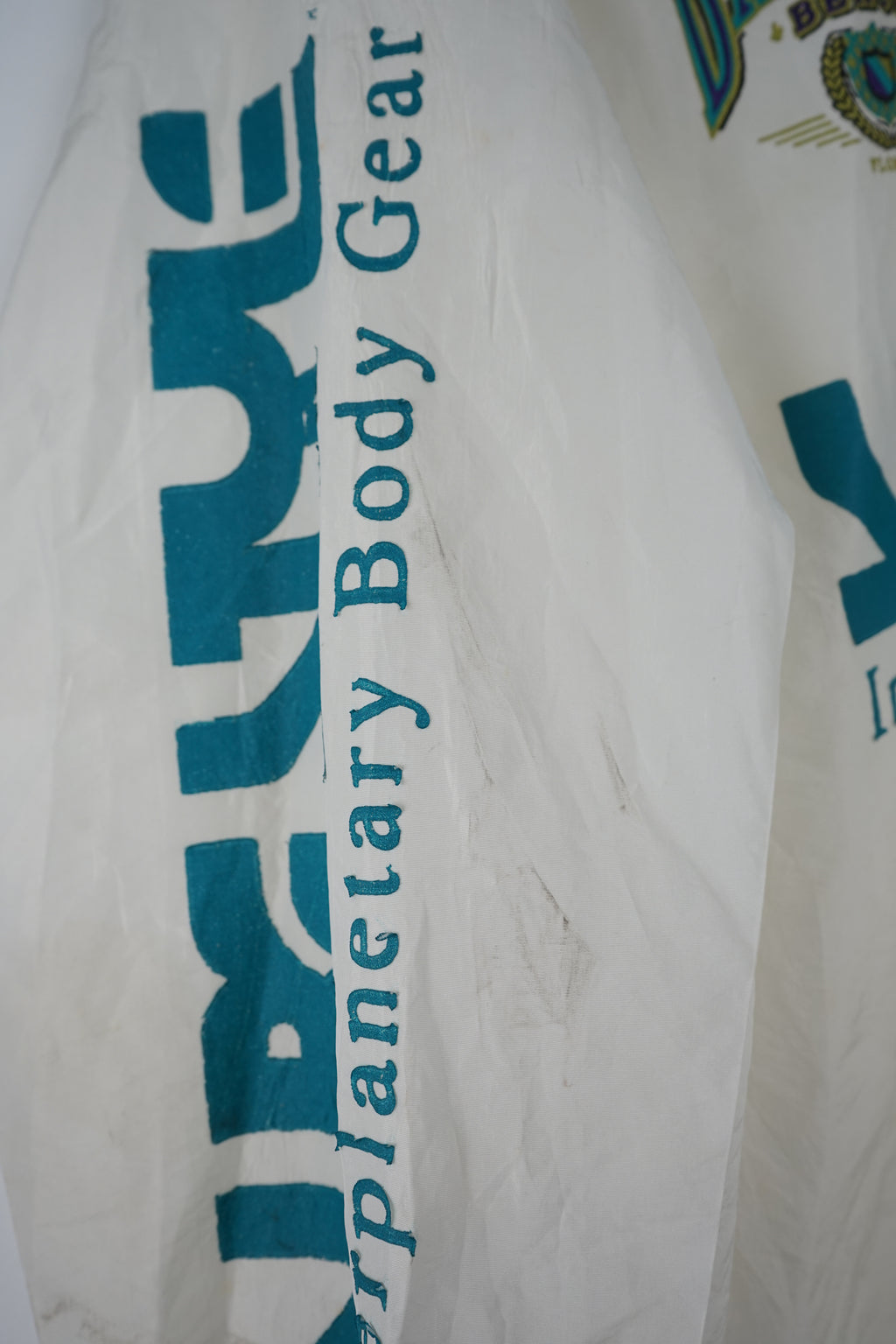 White WINDBREAKER with blue and green text on a white background