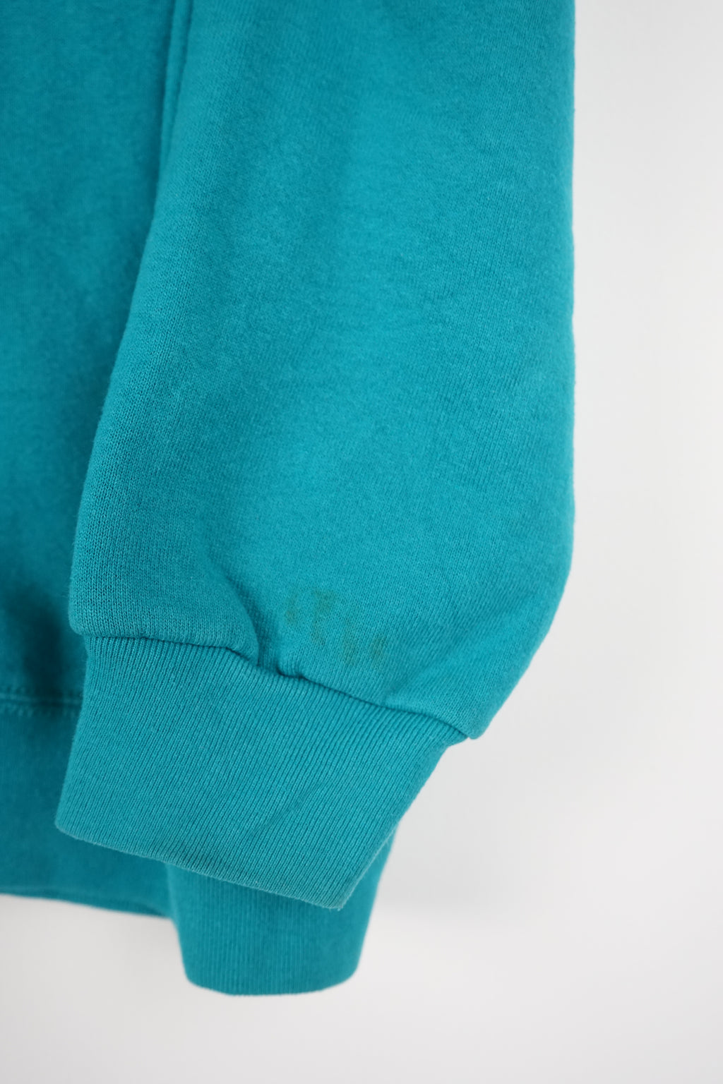 Teal sweatshirt with a small logo on a white background