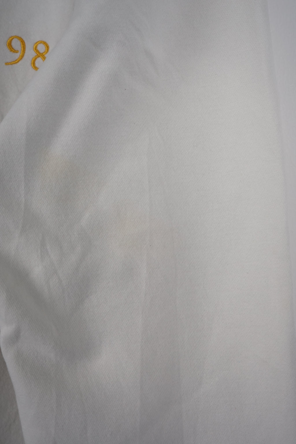 White Tommy Hilfiger sweatshirt on a hanger against a white background
