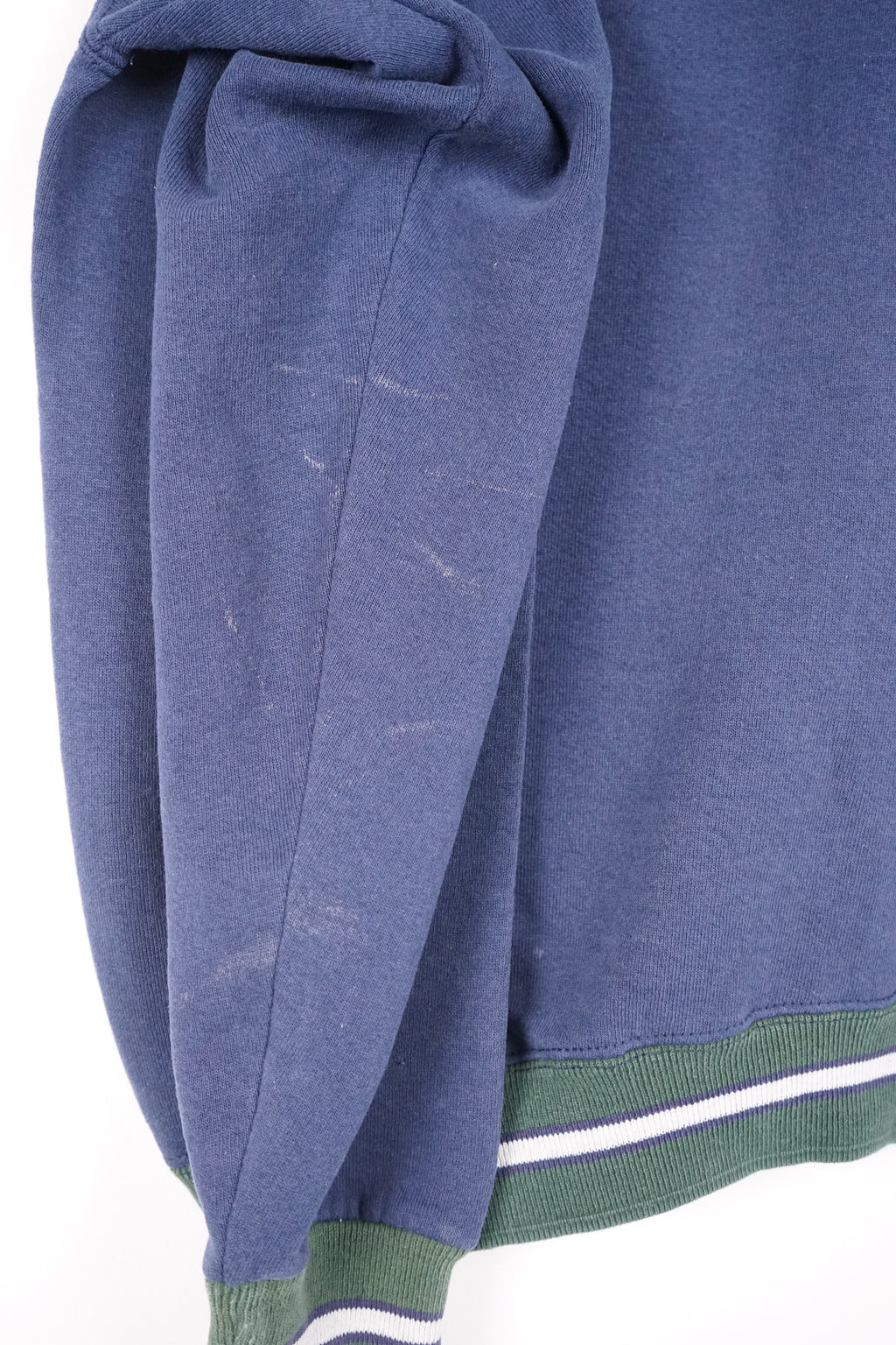 Blue sweatshirt with green and white trim on a hanger against a white background