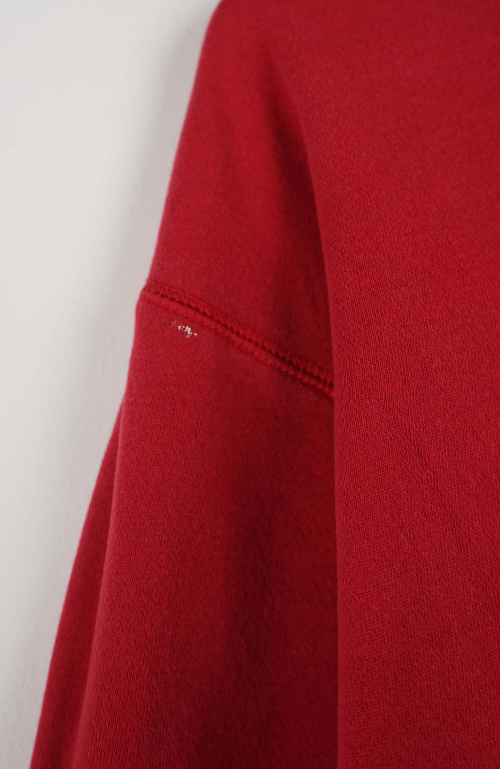 Red sweatshirt with a small logo on a white hanger against a white background