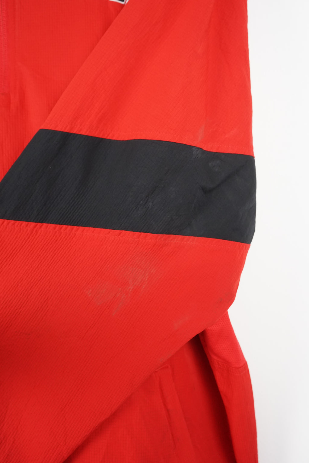 Red sports jacket with black sleeves and logos on a white background