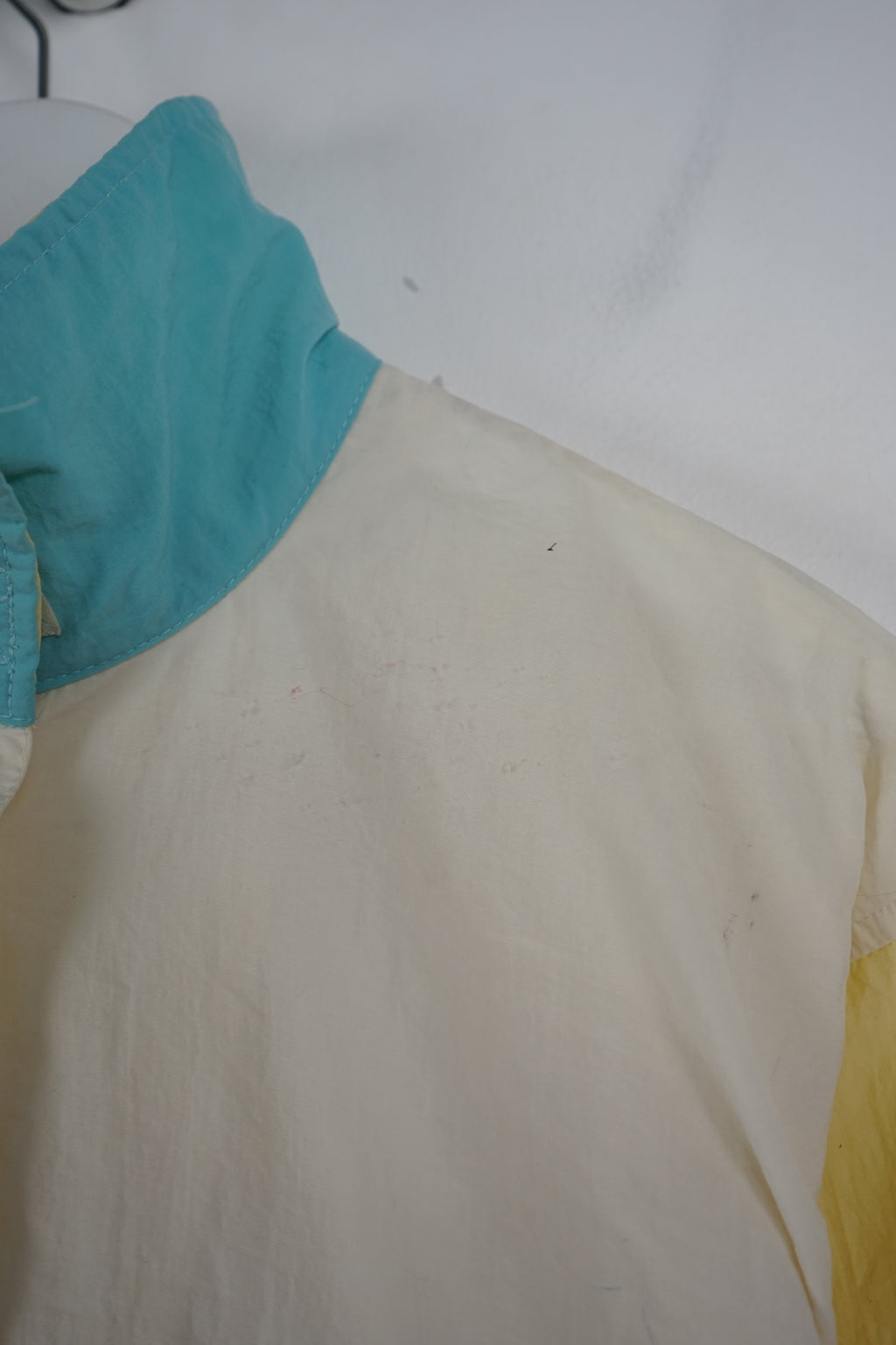 Color-blocked pullover with turquoise and yellow sections on a white background