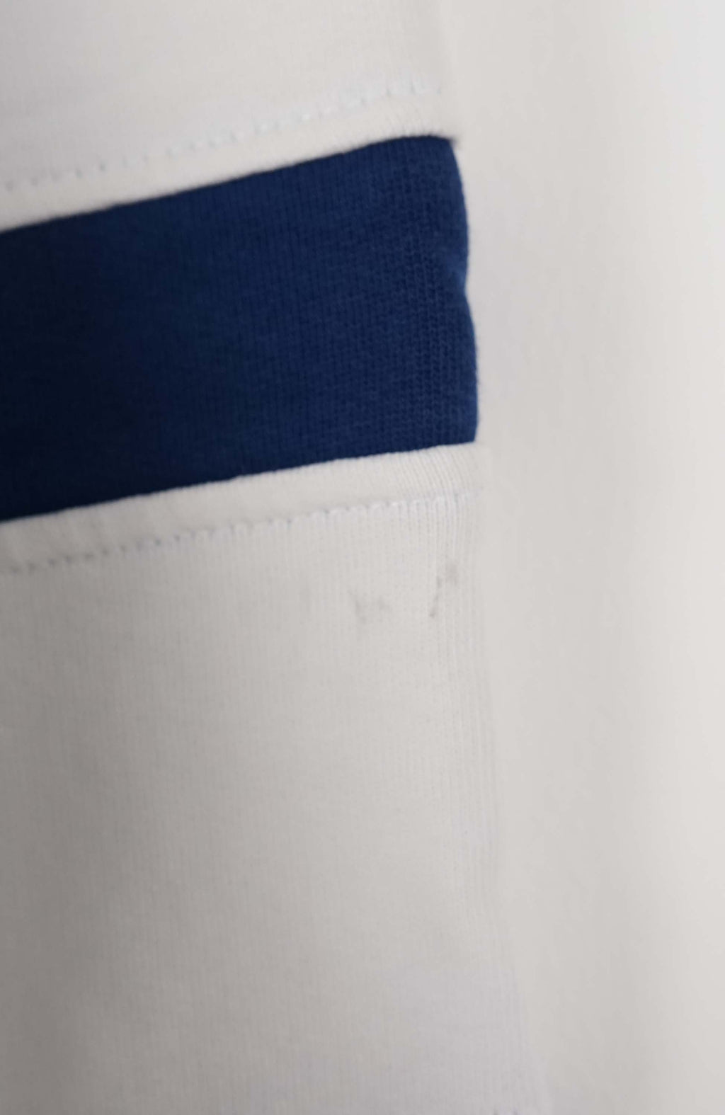 White sweater with blue stripes and red 'Guess' logo on a white background