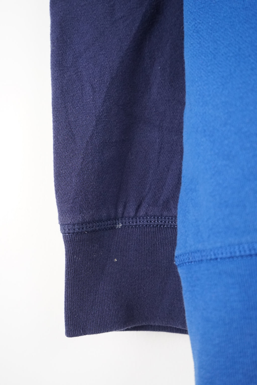 Blue and navy pullover with a brand logo on a white background
