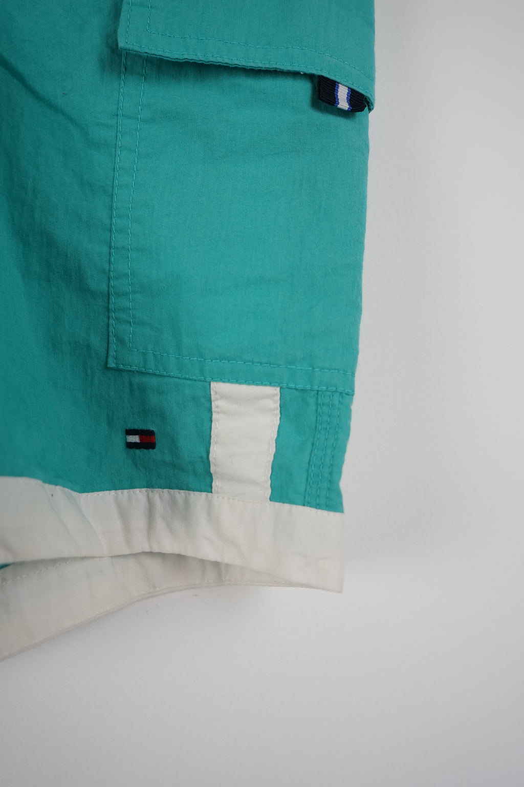 Turquoise shorts with white drawstring and side panels on a white background
