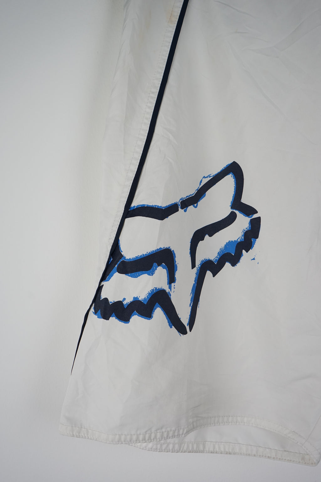 White shorts with a blue logo and black belt on a white background