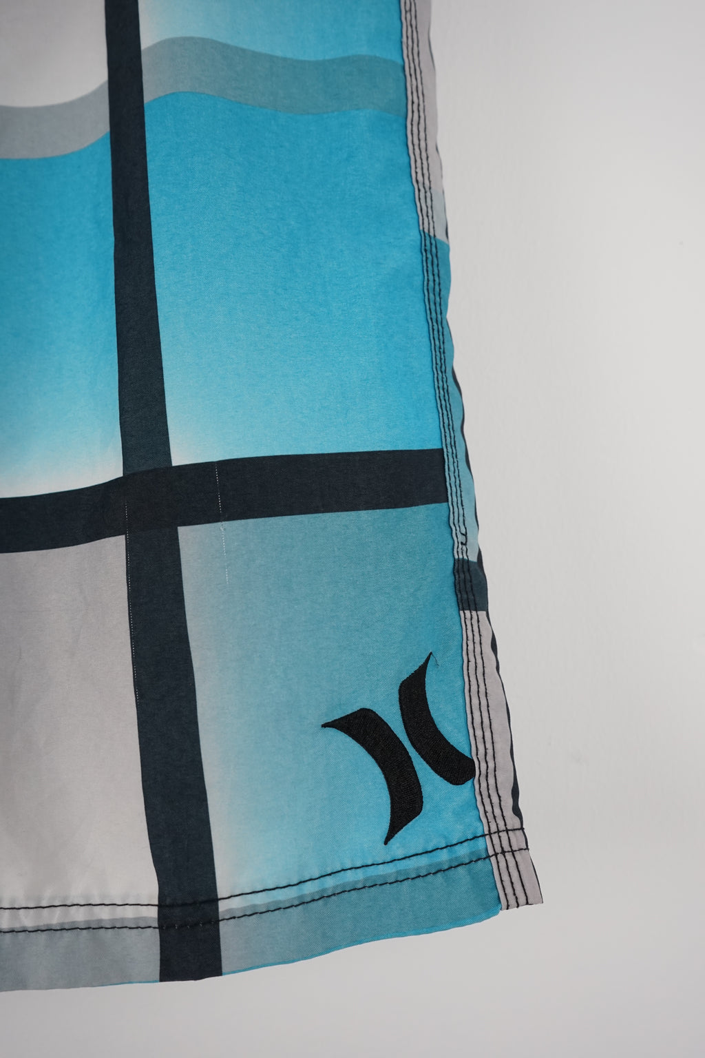 Blue and white checkered shorts with a brand logo on a white background