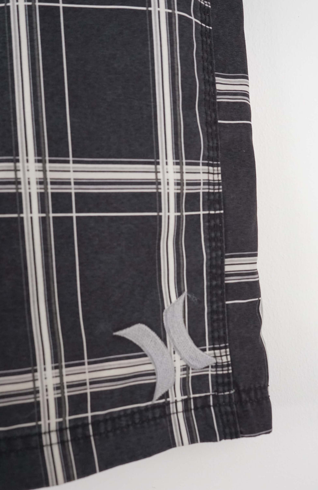 Black and white plaid shorts on a hanger against a white background