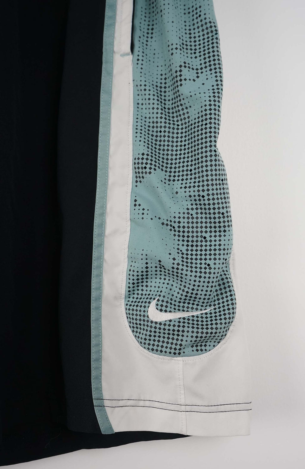 Black athletic pants with mesh side panels on a white hanger