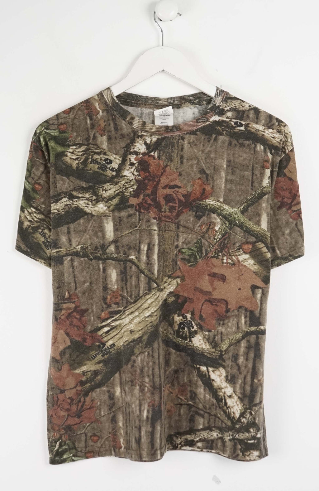 Camouflage-patterned t-shirt with forest design on a white background
