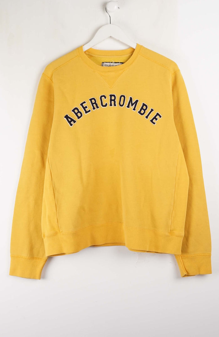 Yellow Abercrombie sweatshirt on a white hanger against a white background