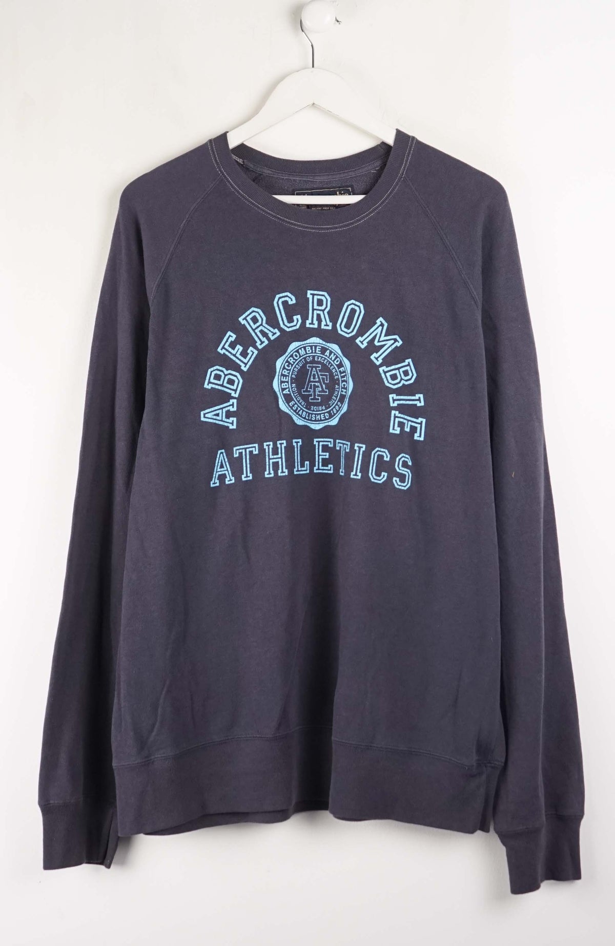 Navy blue Abercrombie sweatshirt on a white hanger against a white background