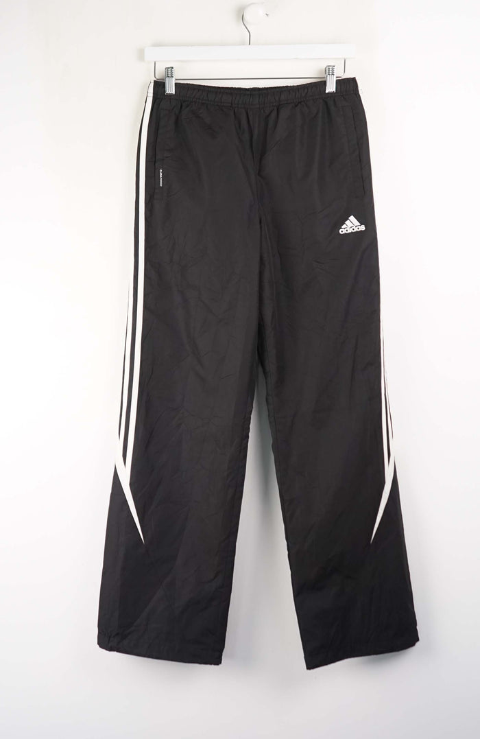 Black Adidas tracksuit pants with white stripes on a white background