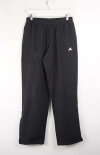 Black Adidas pants hanging on a white background