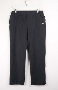 Black Adidas pants on a white hanger against a white background