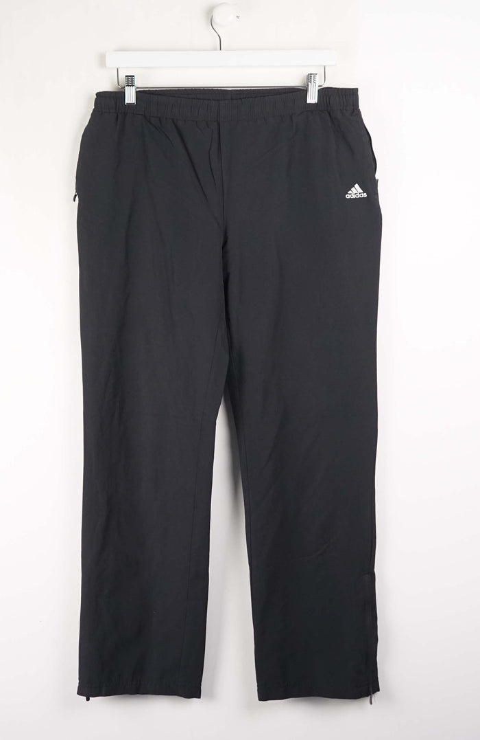 Black Adidas pants on a white hanger against a white background