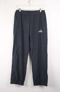 Black Adidas pants hanging on a white background
