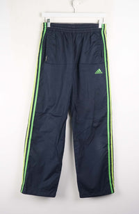 Navy blue tracksuit pants with green stripes and Adidas logo on a white background