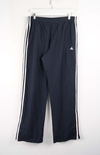 Navy blue Adidas tracksuit pants with white stripes on a white background