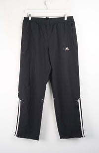 Black Adidas pants with white stripes on a white background