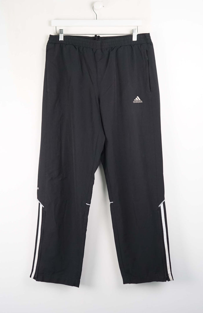 Black Adidas pants with white stripes on a white background