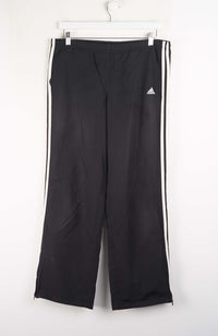 Black Adidas tracksuit pants with white stripes on a white background
