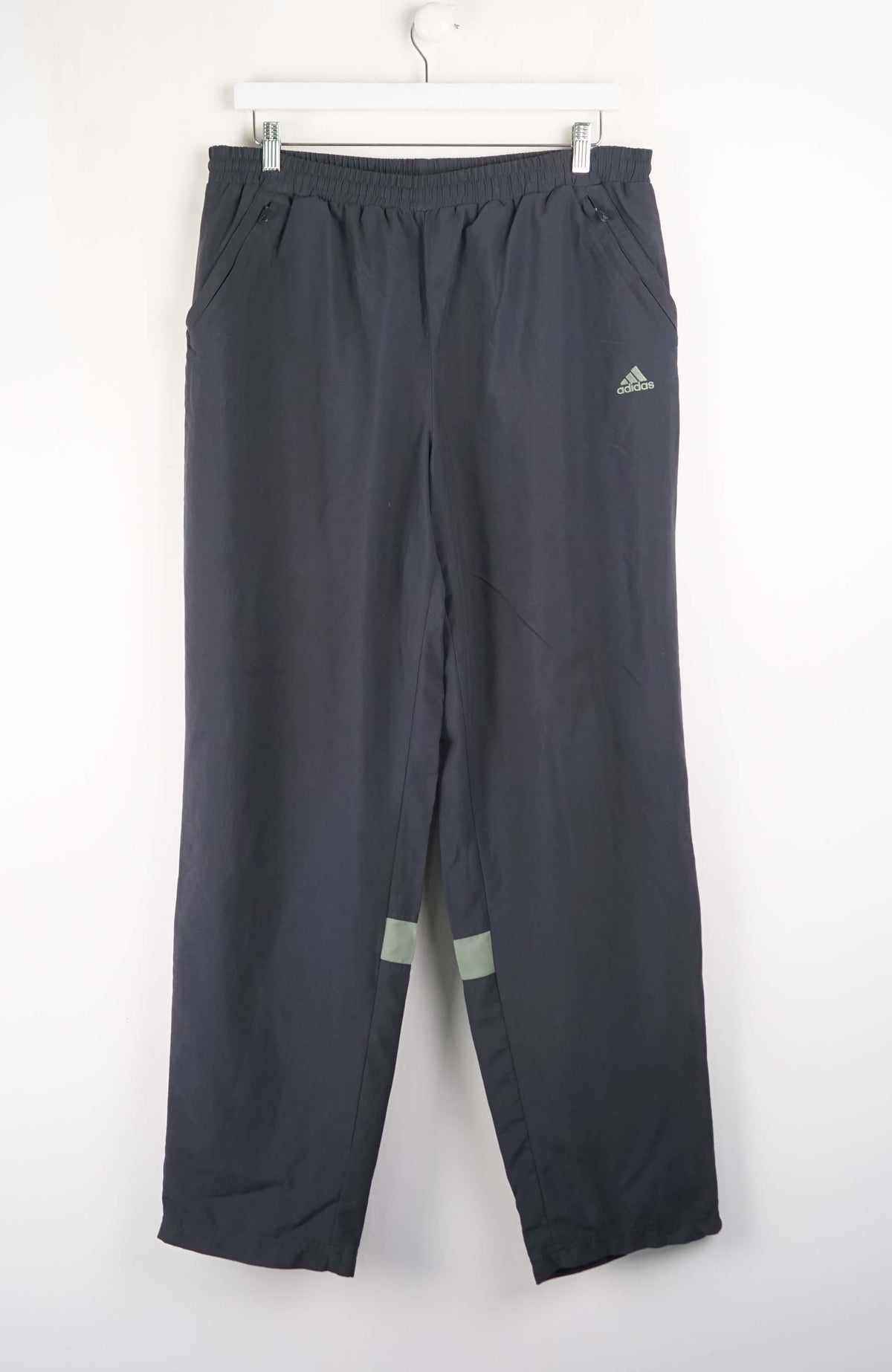 Gray Adidas pants hanging on a white background
