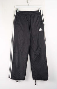 Black Adidas tracksuit pants with white stripes on a white background