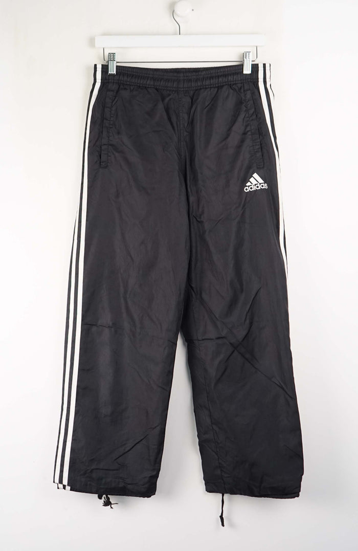 Black Adidas tracksuit pants with white stripes on a white background