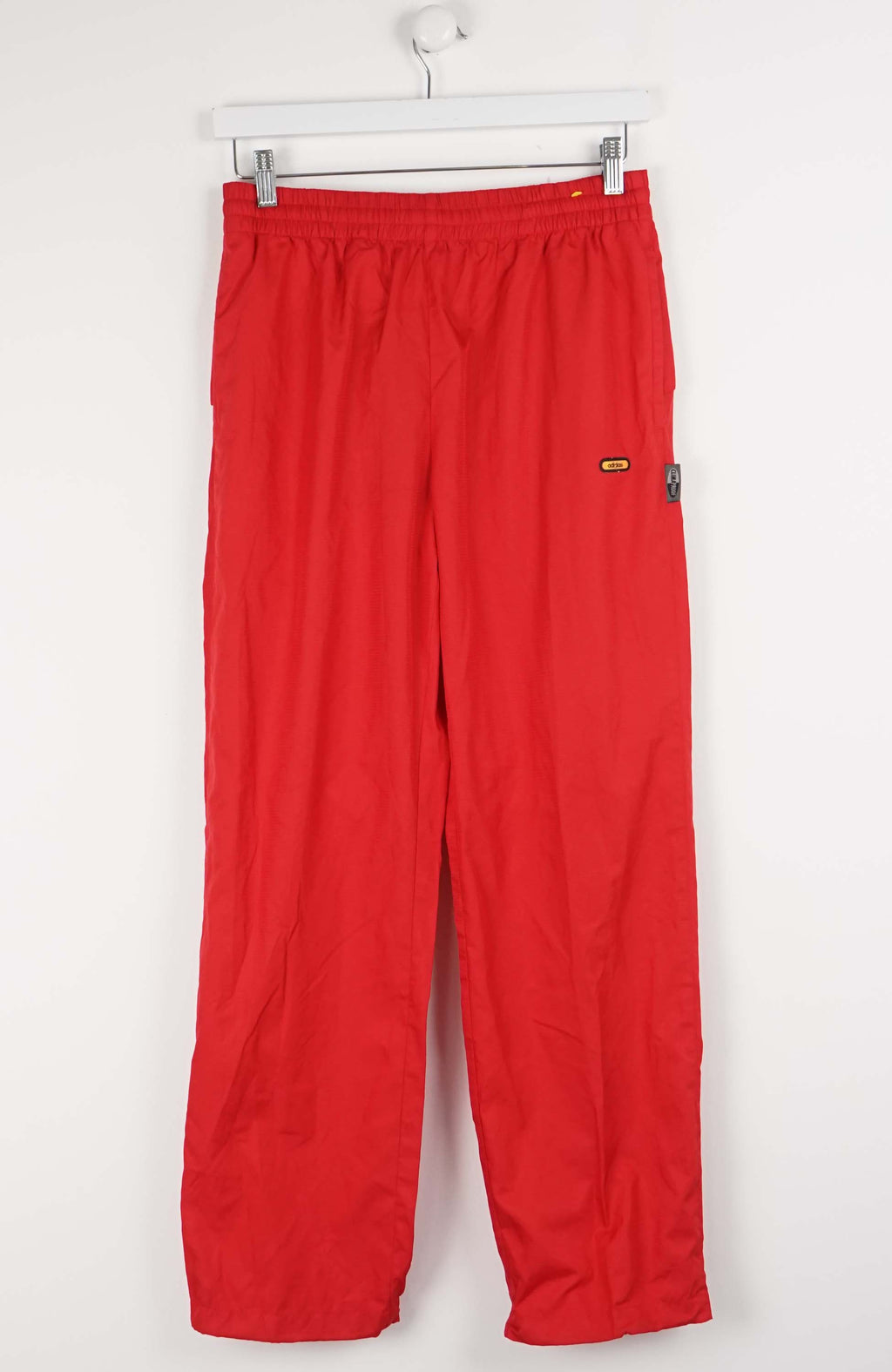 Red pants hanging on a white rack against a white background