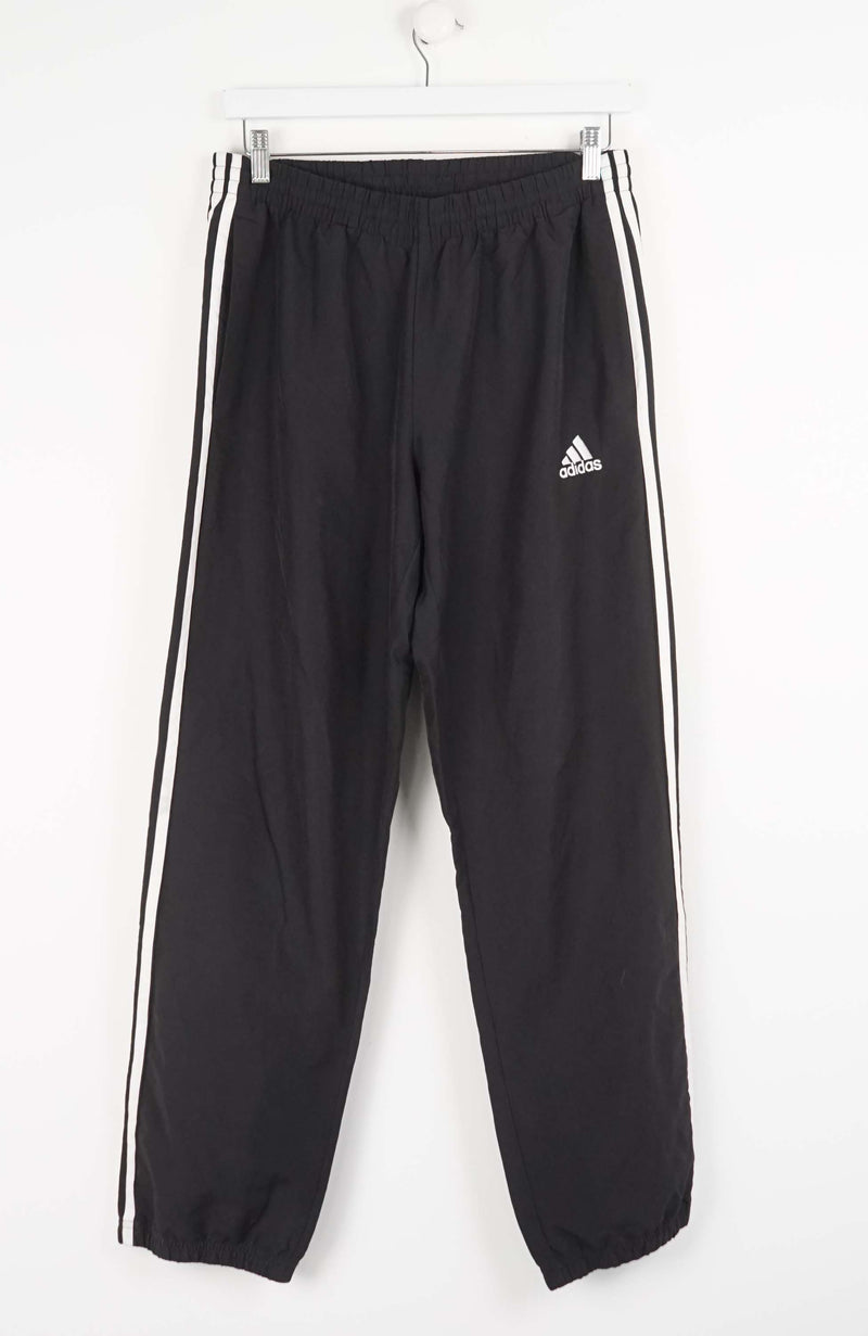 Black Adidas tracksuit pants with white stripes on a white background
